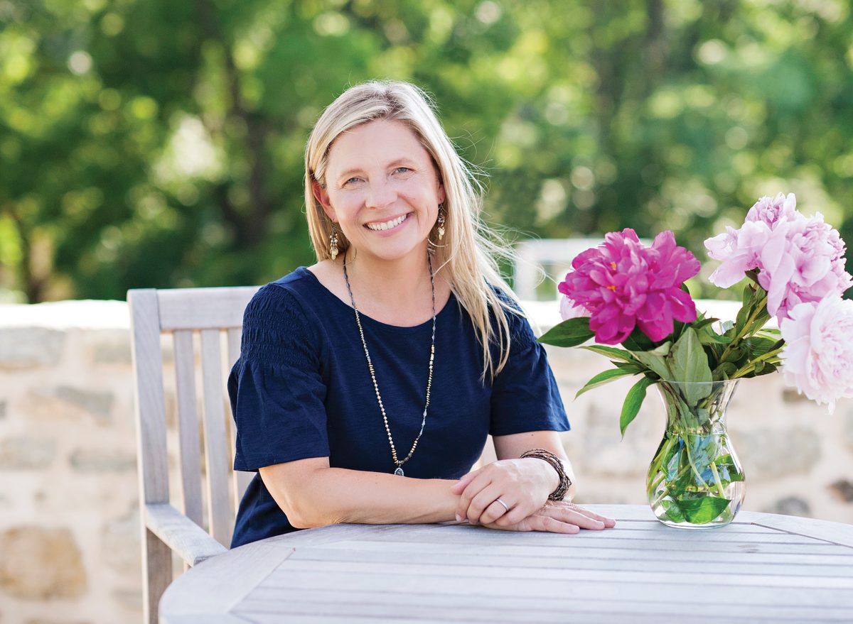 Julie Gates, ADHD coach in West Chester, PA, smiling at an outdoor table with fresh peonies.